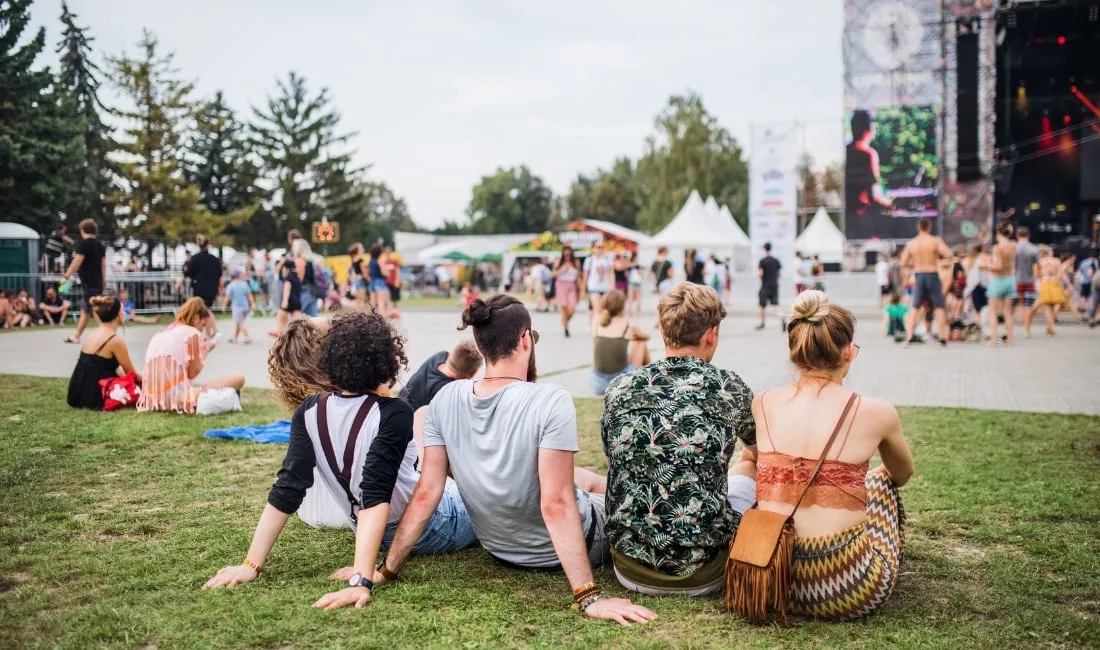 People sitting on grass watching a festival