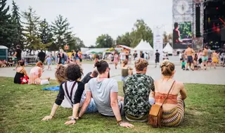 People sitting on grass watching a festival
