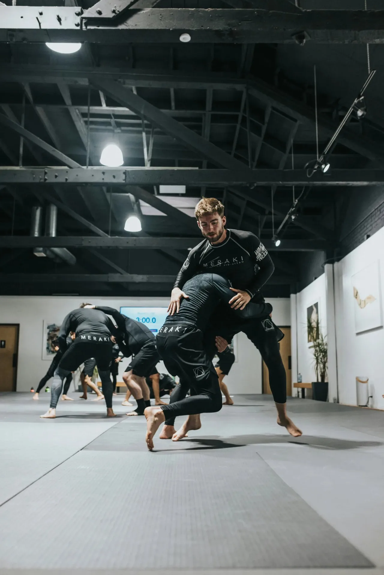 People in black training gear grappling on grey mats