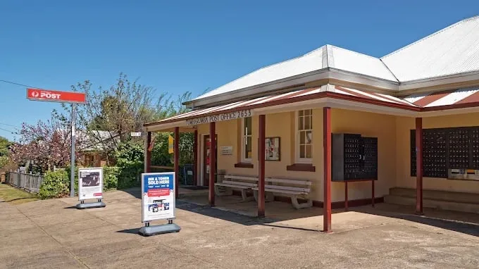 A post office building with a red and white sign