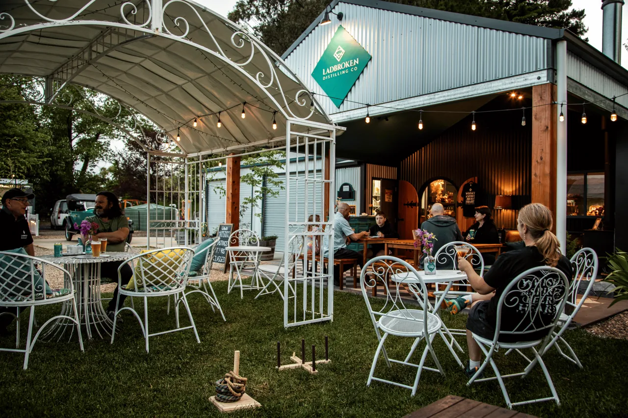 People sitting at tables outside a distillery